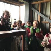 Pupils from Fakenham Junior School learning about Sir Peter from Derek Thompson in the commentary box